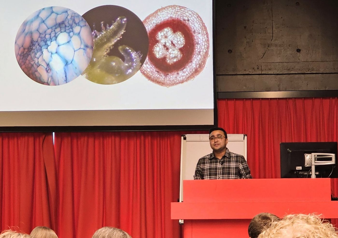 Kailash speaking at a lectern with microscopy images on screen